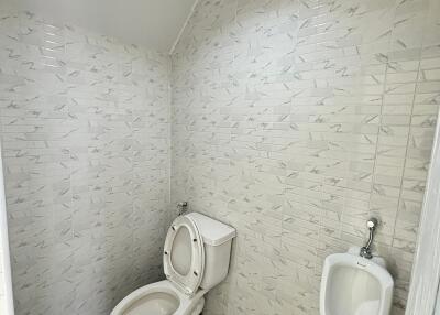 Bathroom with tiled walls, toilet, and urinal