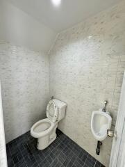 Bathroom with tiled walls, toilet, and urinal