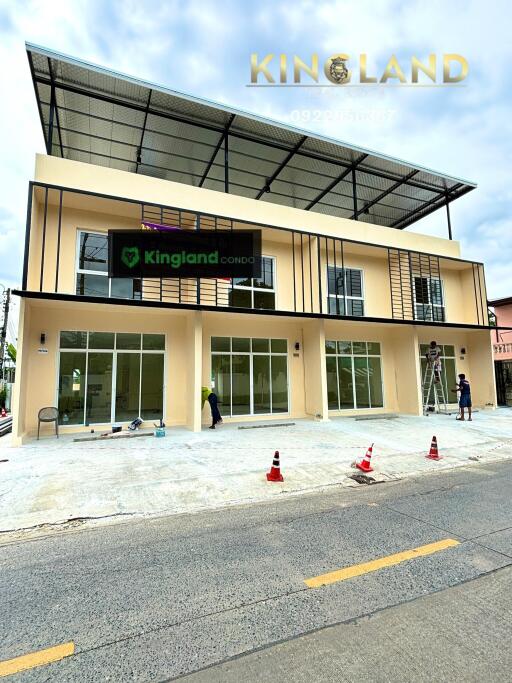 Exterior view of building under construction with large glass windows and a sign reading 