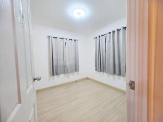 Bedroom with light wooden flooring and gray curtains