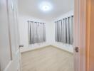 Bedroom with light wooden flooring and gray curtains