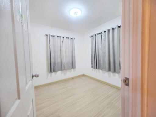 Bedroom with light wooden flooring and gray curtains