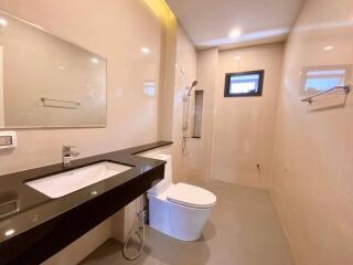 Modern bathroom with beige tiles, large mirror, and shower area