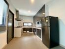 Modern kitchen with black and white cabinets, stainless steel fridge, and gas stove