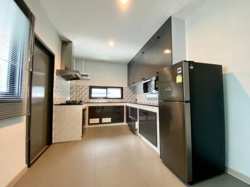 Modern kitchen with black and white cabinets, stainless steel fridge, and gas stove