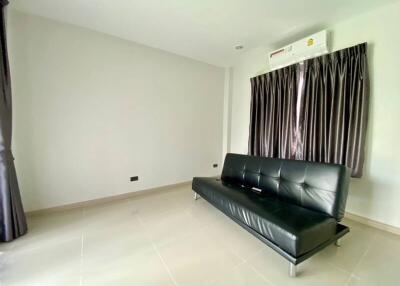 Minimalist living room with black leather couch and air conditioning.