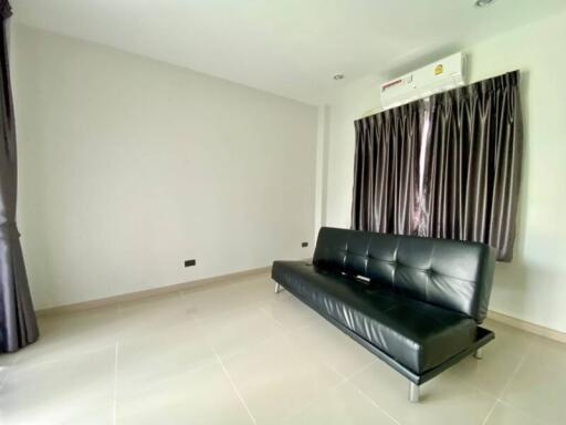 Minimalist living room with black leather couch and air conditioning.