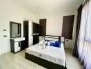 Modern furnished bedroom with bed, wardrobe, and vanity