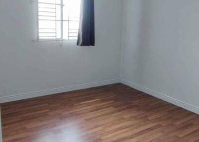 Empty bedroom with wooden floor and window with a curtain