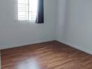 Empty bedroom with wooden floor and window