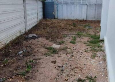 Unpaved backyard area with fencing and neighboring building