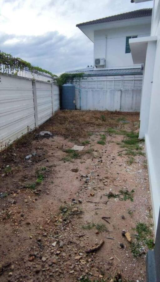 Unpaved backyard area with fencing and neighboring building