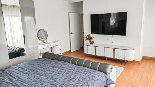 Modern bedroom with large TV and stylish furniture