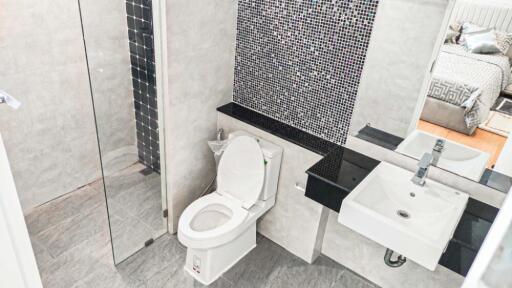 Modern bathroom with glass shower, toilet, and sink with black countertop.