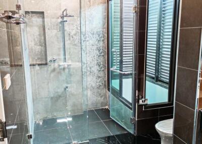 Modern bathroom with glass shower enclosure and black tile flooring