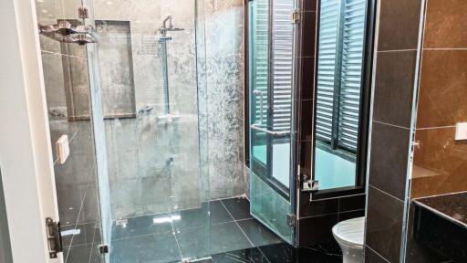 Modern bathroom with glass shower enclosure and black tile flooring