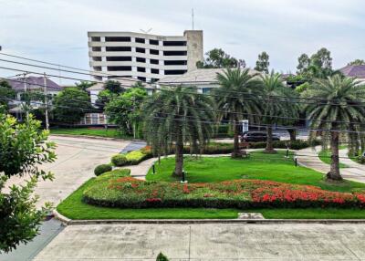 View from the property showing green landscaped gardens with trees and a building in the background