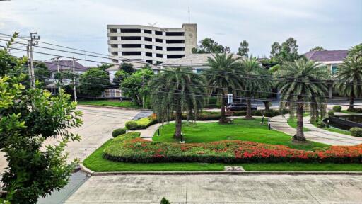 View from the property showing green landscaped gardens with trees and a building in the background