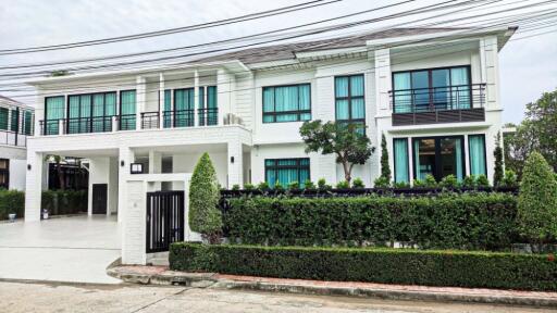 Modern two-story house with large windows and green surroundings