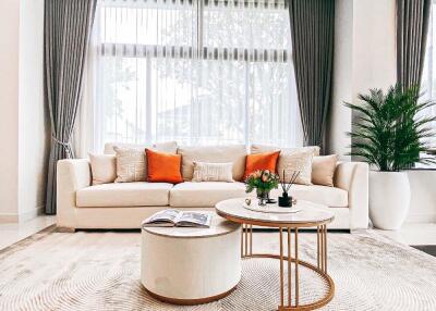 Modern living room with white sofa, coffee tables, and large window with curtains