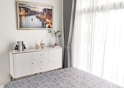 Bright bedroom with large window, white dresser, and decor