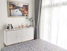 Bright bedroom with large window, white dresser, and decor