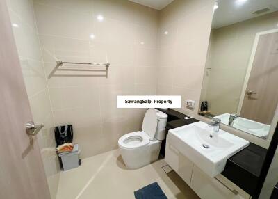 Modern bathroom with toilet, sink, mirror, and towel rack