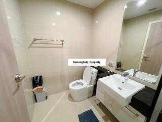 Modern bathroom with toilet, sink, mirror, and towel rack