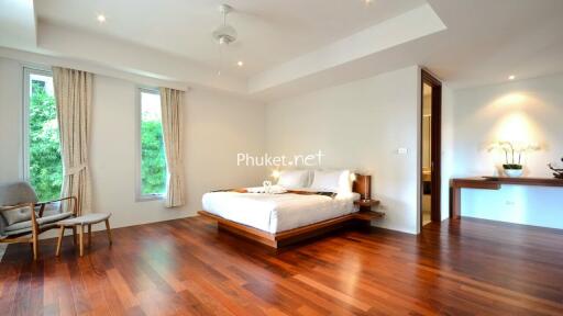 Spacious, modern bedroom with wooden flooring and large windows