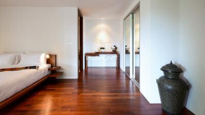 spacious bedroom with wooden flooring and decorative elements