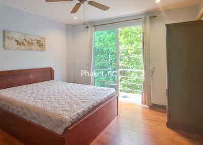 Well-lit bedroom with a bed, large window, and wardrobe