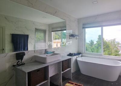 Modern bathroom with a large window and a freestanding bathtub