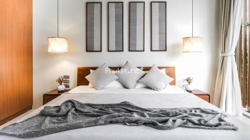 Modern bedroom with a large bed, pillows, bedside tables, hanging lamps, and wall art