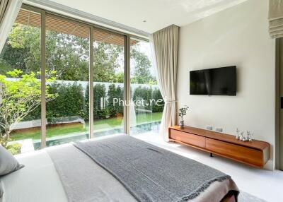 Modern bedroom with large windows overlooking a garden and pool