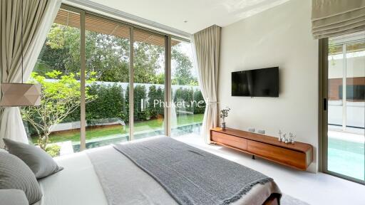 Modern bedroom with large windows overlooking a garden and pool