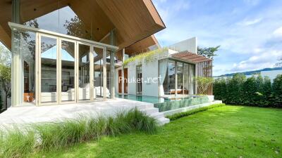 Modern house with floor-to-ceiling windows, outdoor pool, and green lawn