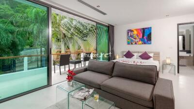 Modern bedroom with large glass windows and a lush outdoor view