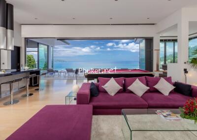 Modern living room with ocean view, purple sofa, and open kitchen