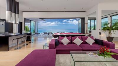 Modern living room with ocean view, purple sofa, and open kitchen