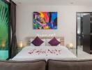 Modern bedroom with a large bed, colorful artwork, and glass side tables