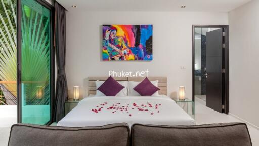 Modern bedroom with a large bed, colorful artwork, and glass side tables