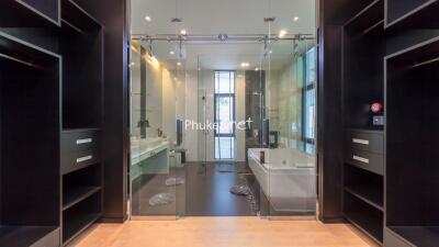 Modern bathroom with glass doors, large mirrors, and built-in storage