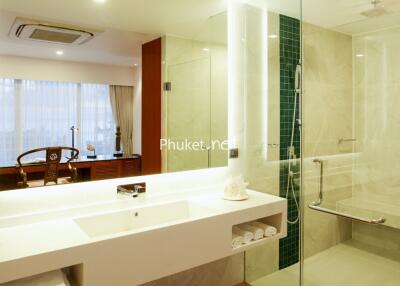 Modern bathroom with a large vanity mirror, white countertop, glass-enclosed shower, and decorative items