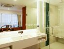 Modern bathroom with a large vanity mirror, white countertop, glass-enclosed shower, and decorative items