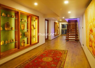 Warmly lit hallway with decorative shelves and wooden staircase