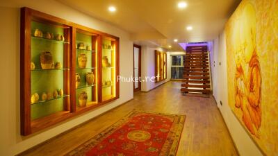 Warmly lit hallway with decorative shelves and wooden staircase