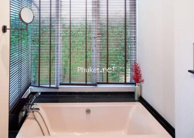 Bathroom with a bathtub and large window with blinds