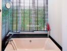 Bathroom with a bathtub and large window with blinds