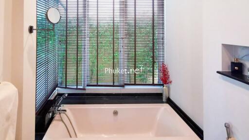 Bathroom with a bathtub and large window with blinds