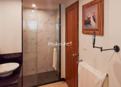 Modern bathroom with glass shower, wooden door, and wall-mounted sink